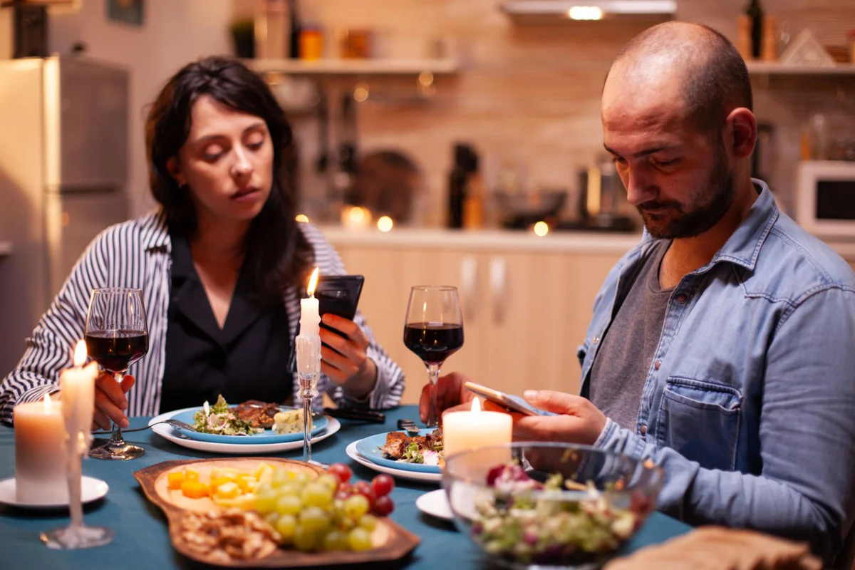 A long-term couple sitting quietly together at home looking a little distant and bored, illustrating what it means to feel bored in a long-term relationship and how to bring the spark back