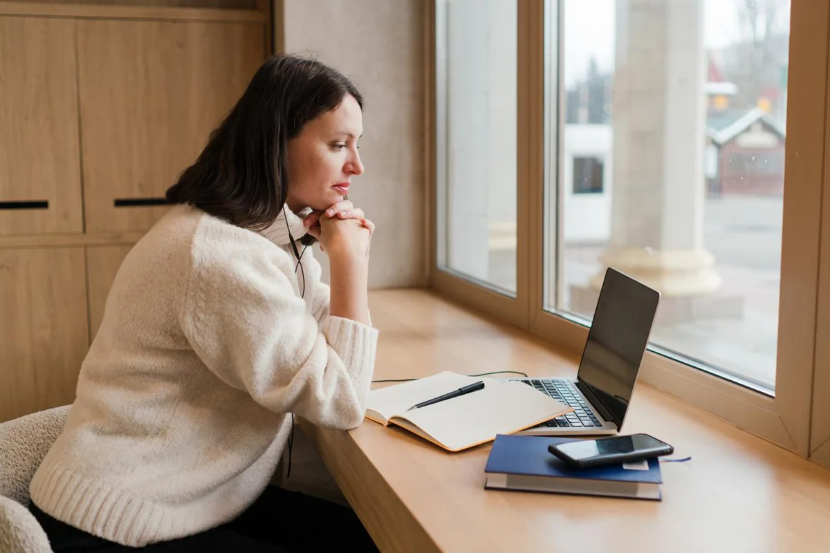 A person thoughtfully comparing online counselling options on a laptop at home, illustrating how to choose the right online counselling service and what actually matters
