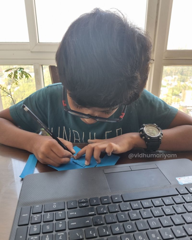 A child writing at a desk near a bright window
