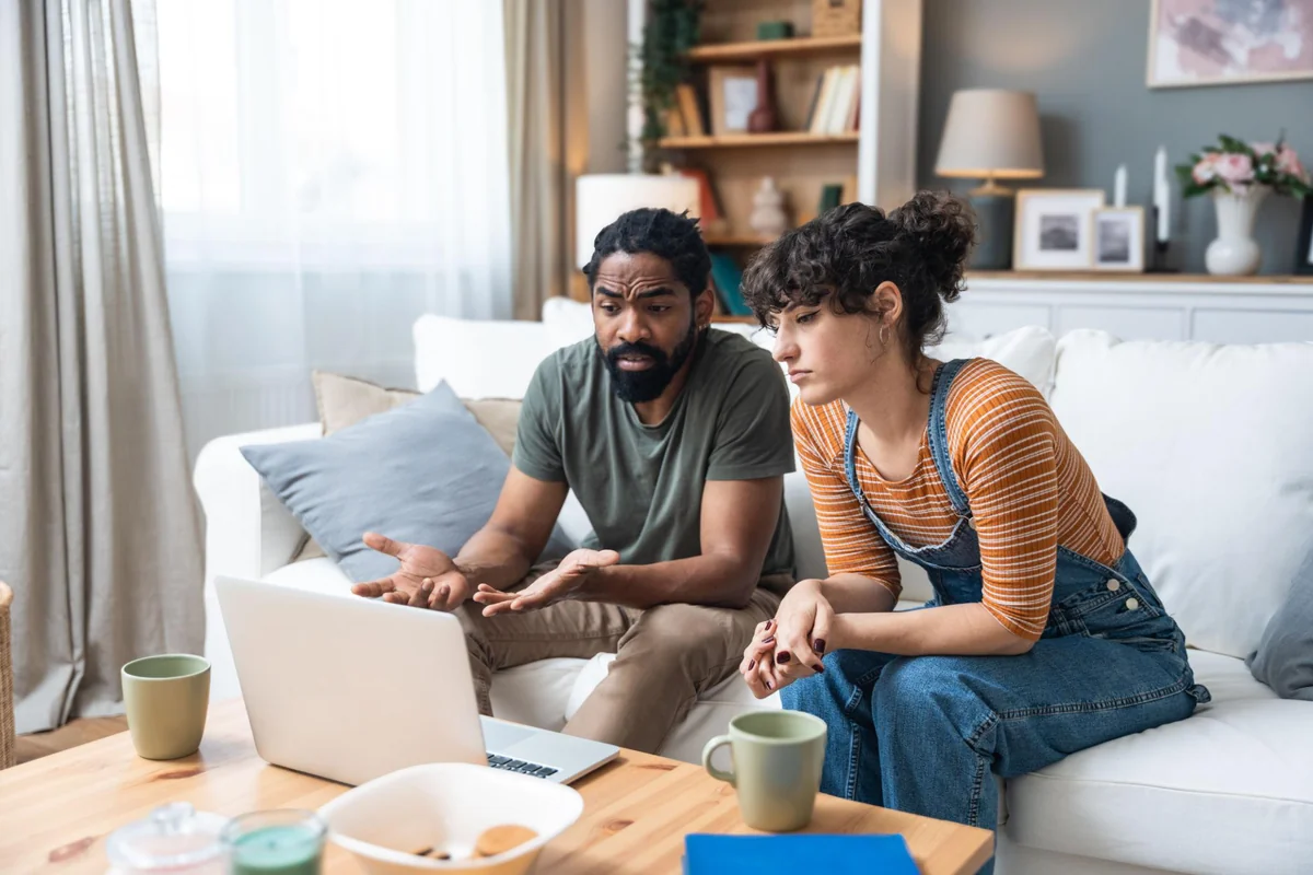 A couple sitting together at home during a video counselling session on a laptop, illustrating how online couples and relationship counselling works and whether it is worth it